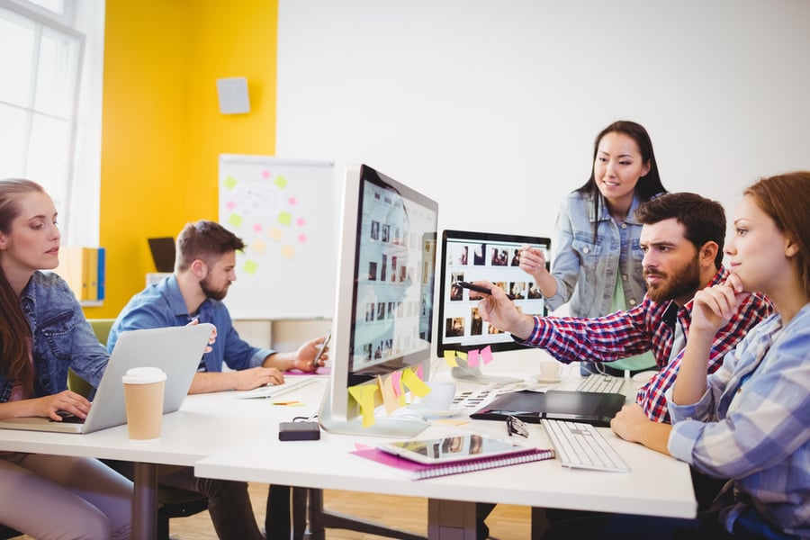 Businessman showing computer screen to coworkers in creative office-1