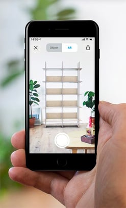 The screen of a mobile phone shows AR technology allowing you to see how furniture will look in your space