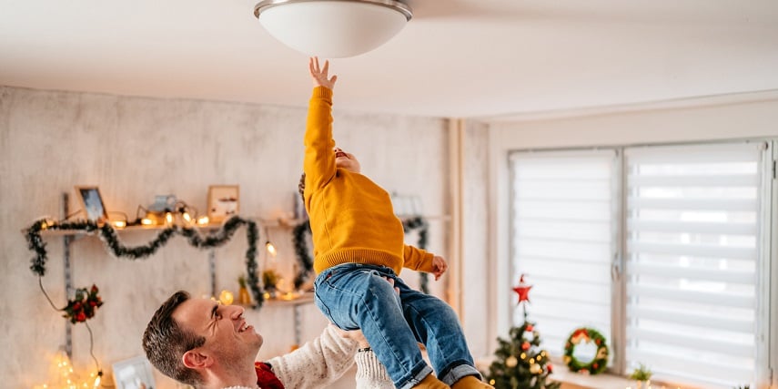 Father holding up child to touch mounted light