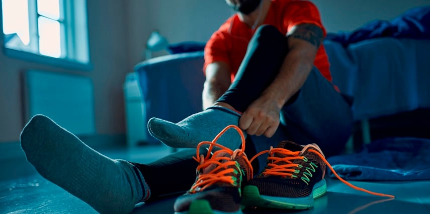 Man putting on custom running shoes he created through an Adidas shoe configurator