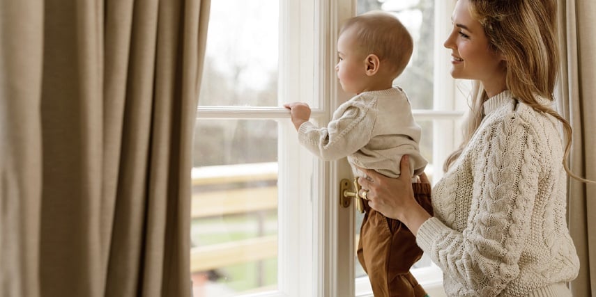Mom and toddler standing by custom curtains she customized on a site with virtual photography