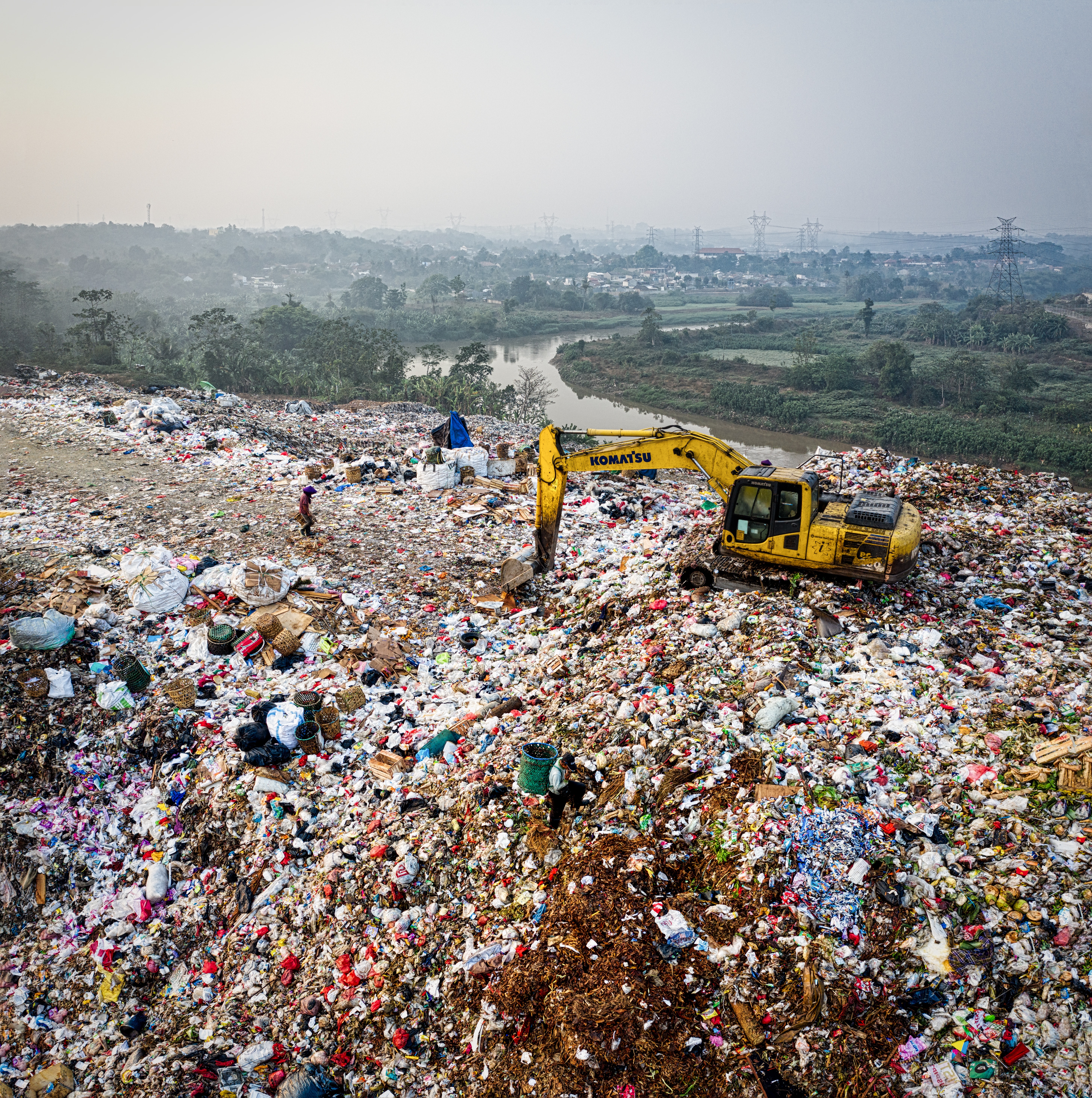 Waste in a landfill with a yellow excavator in the background