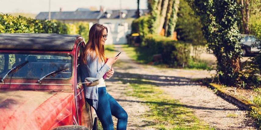 Shopper browsing through a 3D car customization online tool while leaning against their car