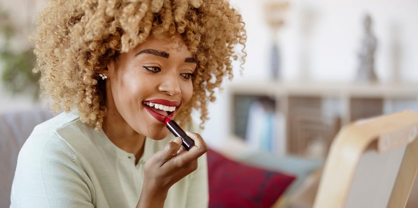 Woman putting on lipstick she purchased after a virtual try-on