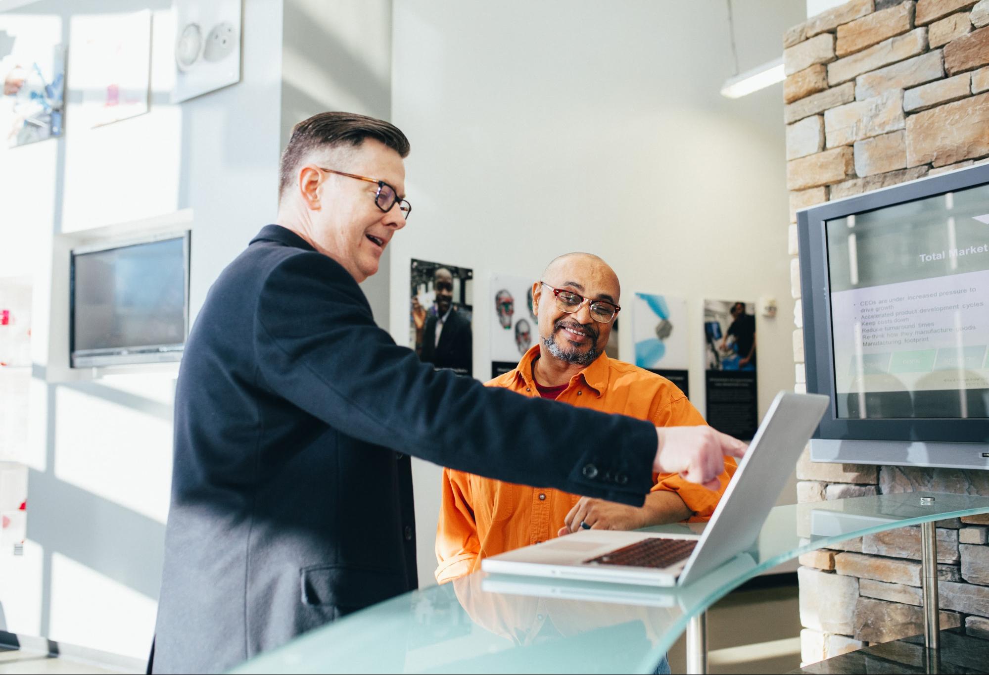 A shop assistant giving a customer an AR experience in a retail store using a laptop 