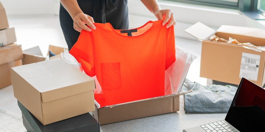 Shopper opening a delivered box of online clothes purchases